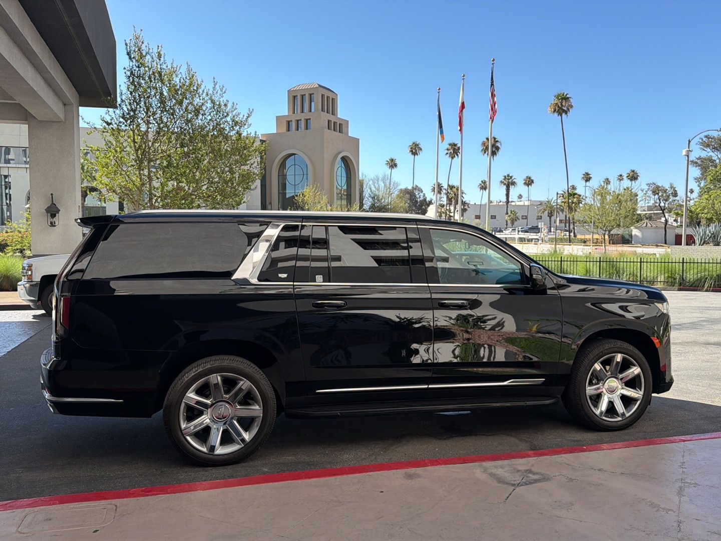 Professional luxury chauffeur service welcoming an elegantly dressed couple beside a luxury black SUV outside an upscale venue, showcasing premium transportation for weddings, corporate events, airport transfers, and special occasions throughout the Inland Empire 2026